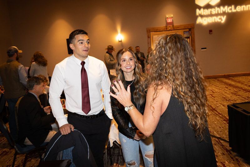 A group of people are standing in a room talking to each other.