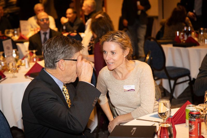 A man and a woman are sitting at a table talking to each other.