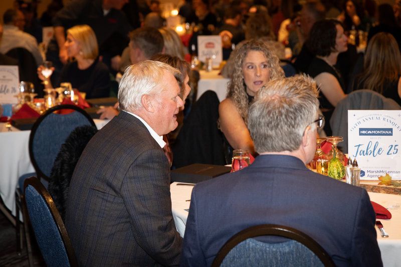 Two men are sitting at a table with a sign that says table 25