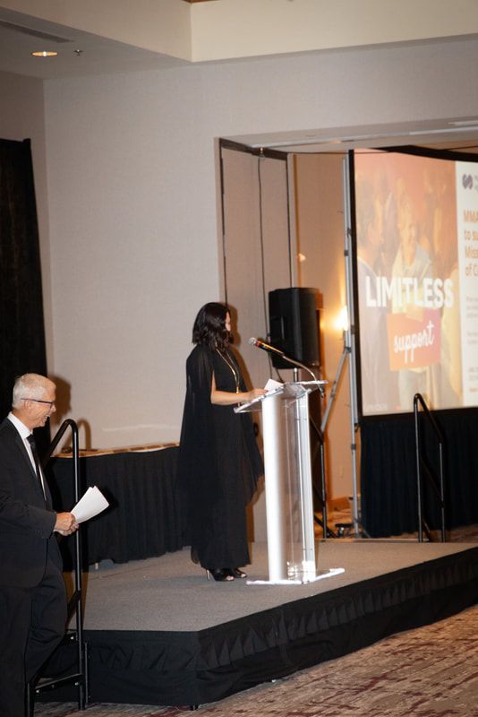 A woman stands at a podium in front of a screen that says limitless