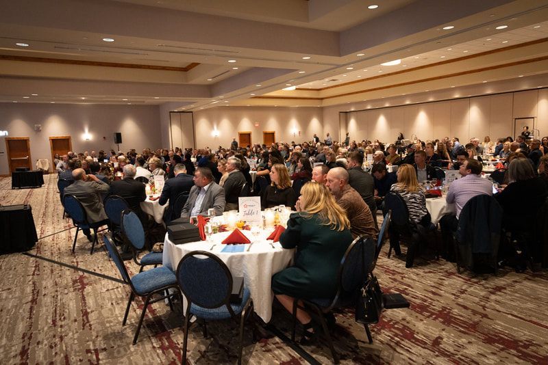 A large group of people are sitting at tables in a large room.