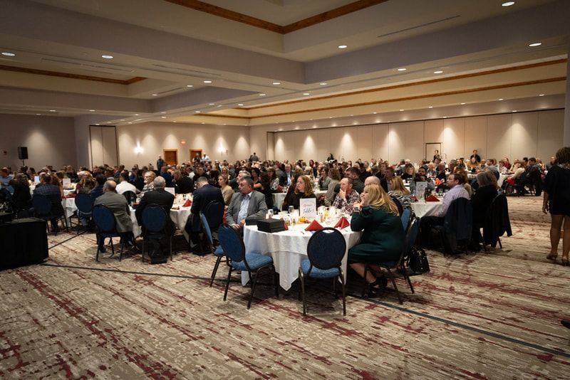 A large group of people are sitting at tables in a large room.