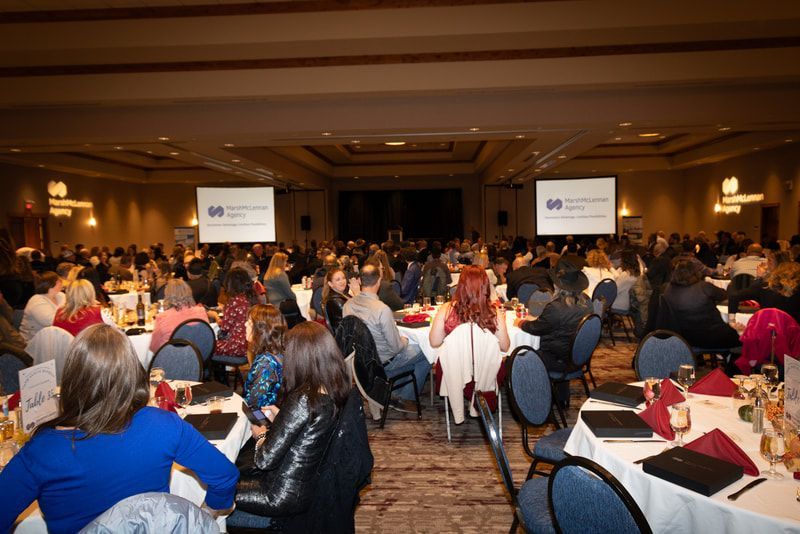 A large group of people are sitting at tables in a large room.