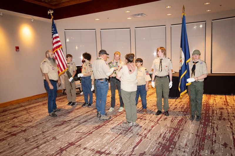 A group of boy scouts are standing in a room with flags.