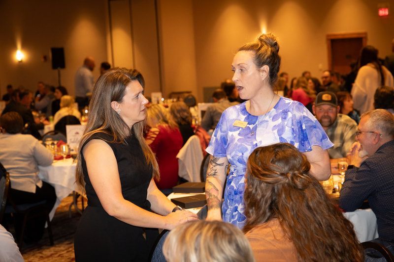 A group of people are sitting at tables in a room talking to each other.