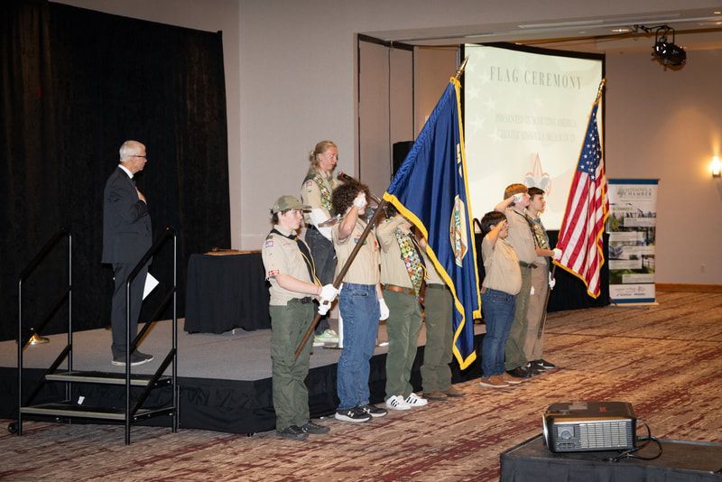 A group of boy scouts holding flags on a stage