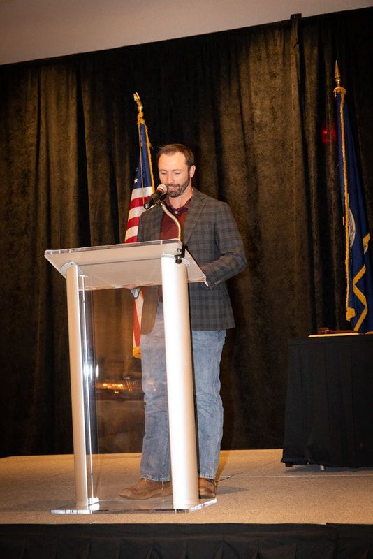 A man is standing at a podium speaking into a microphone.