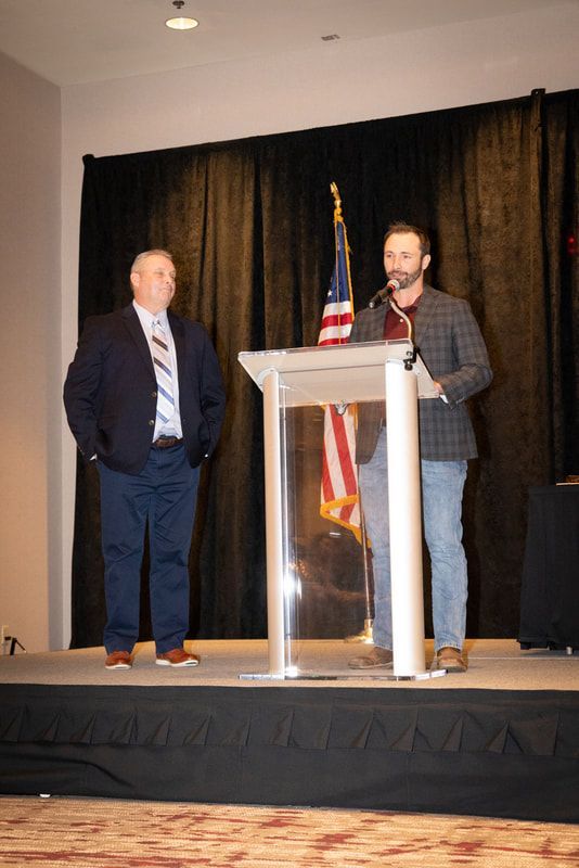 Two men are standing at a podium giving a speech.