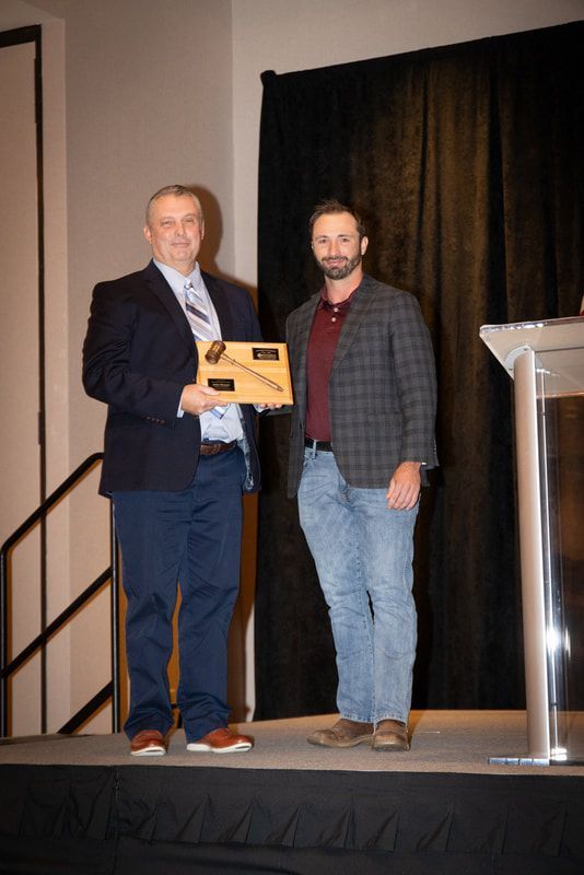 Two men are standing on a stage holding a plaque.