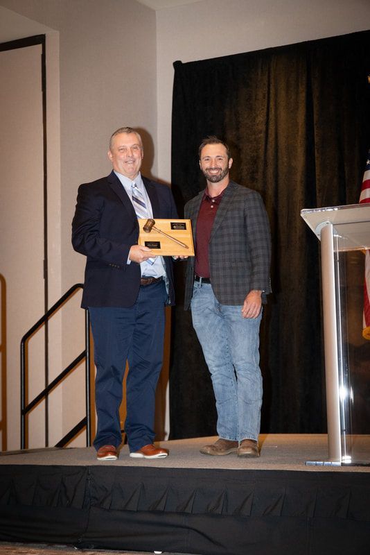 Two men are standing on a stage holding a plaque.
