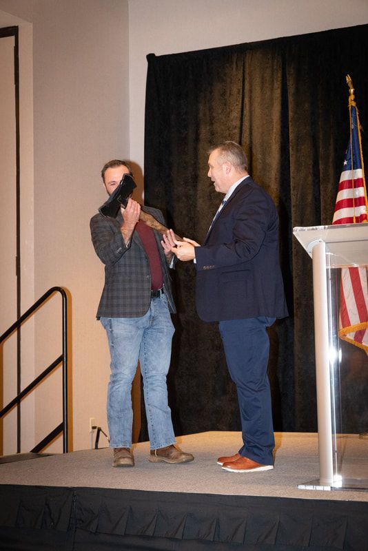 Two men are standing on a stage in front of an american flag.