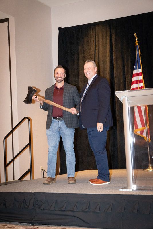 Two men are standing on a stage holding axes.
