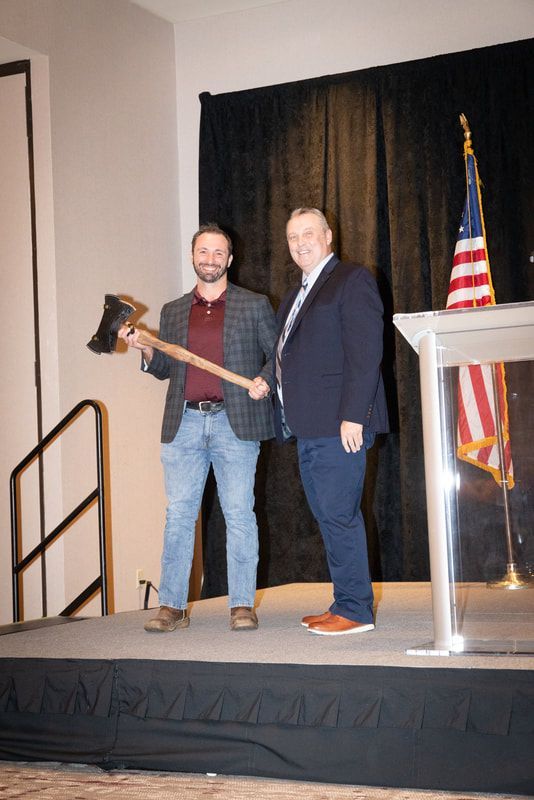 Two men are standing on a stage holding axes.