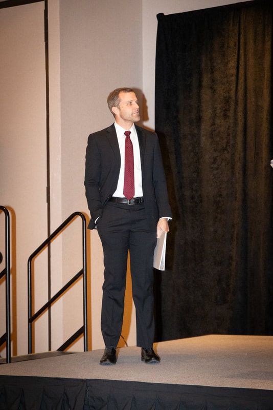 A man in a suit and tie is standing on a stage