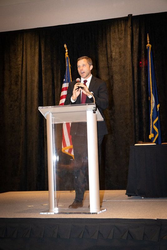A man in a suit and tie is giving a speech at a podium