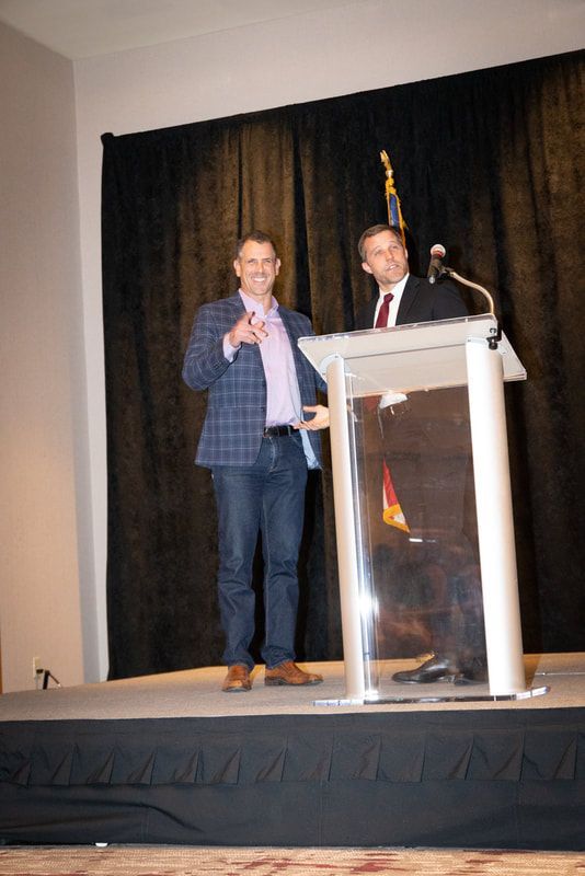 Two men are standing at a podium giving a presentation.