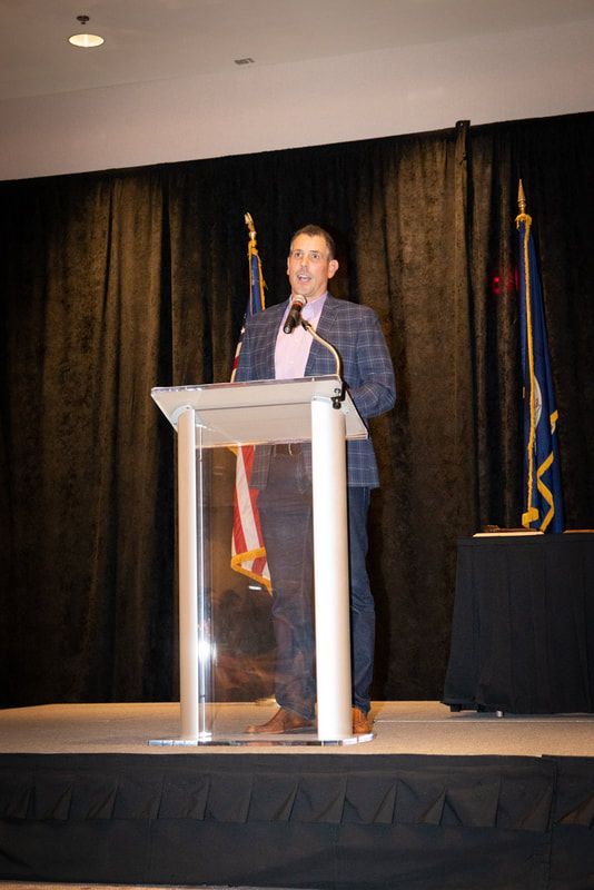 A man is standing at a podium speaking into a microphone
