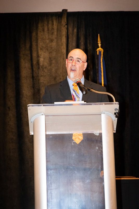A man in a suit and tie is giving a speech at a podium