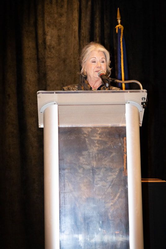 A woman is standing at a podium speaking into a microphone.