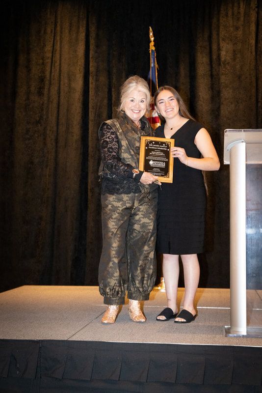 Two women are standing on a stage holding an award.