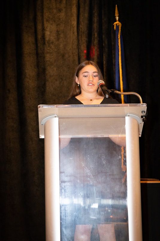 A young woman is standing at a podium giving a speech.