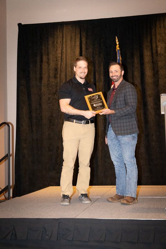 Two men are standing on a stage holding a plaque.
