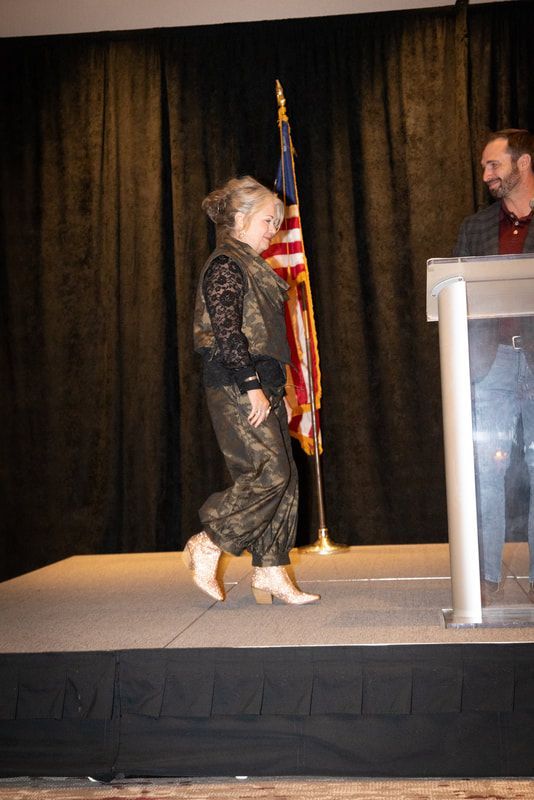 A woman is walking on a stage next to an american flag
