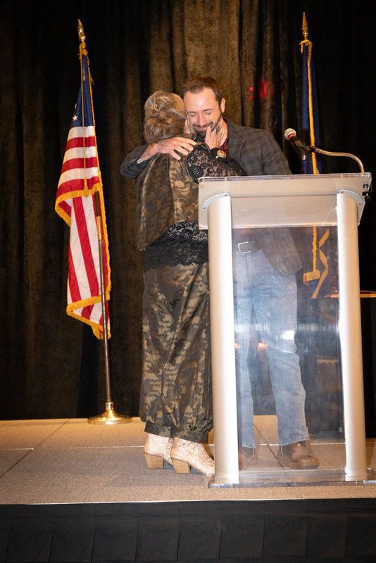 A man is hugging a woman while standing at a podium.