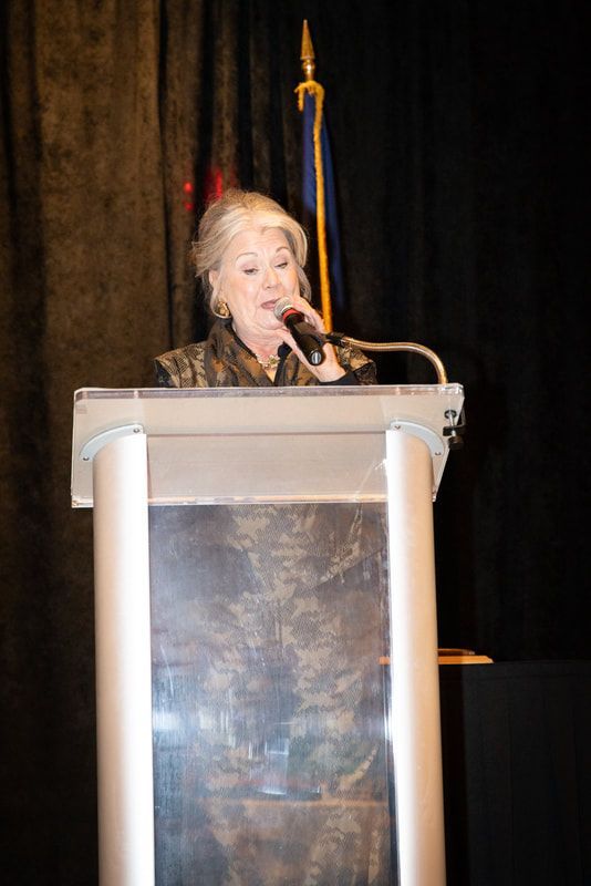 A woman is standing at a podium speaking into a microphone.