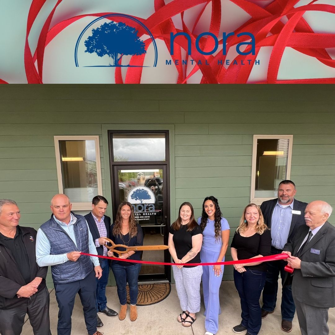 A group of people cutting a red ribbon in front of a building that says nora