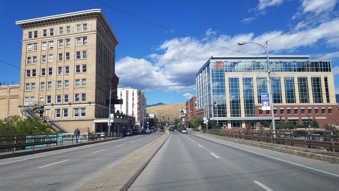 A city street with a large building in the background and a large building in the foreground.