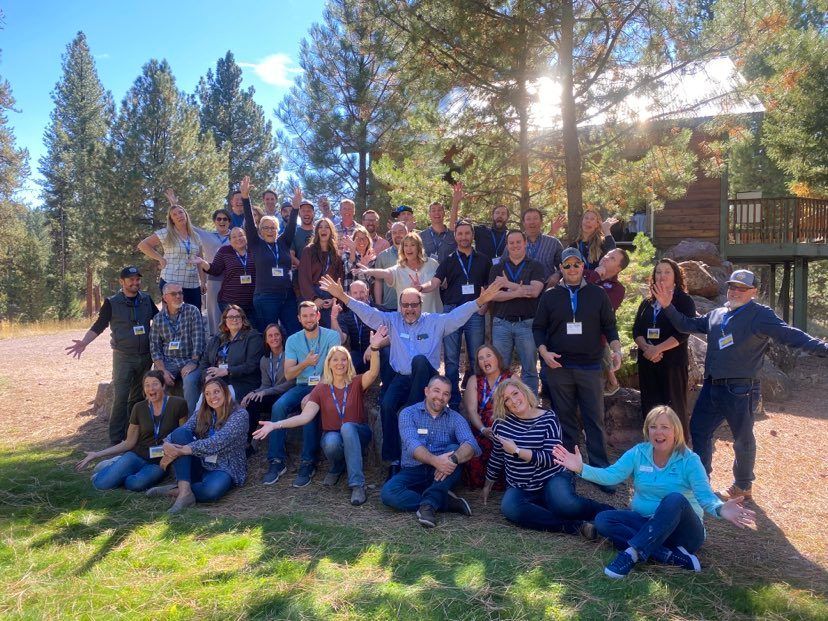 A group of people are posing for a picture in front of a cabin.