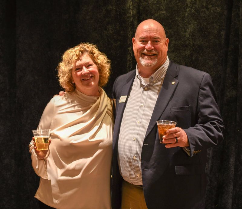A man and a woman are posing for a picture while holding drinks