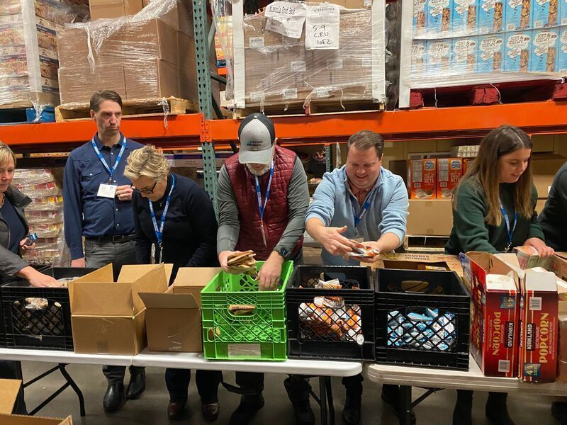 A group of people are standing around a table in a warehouse.