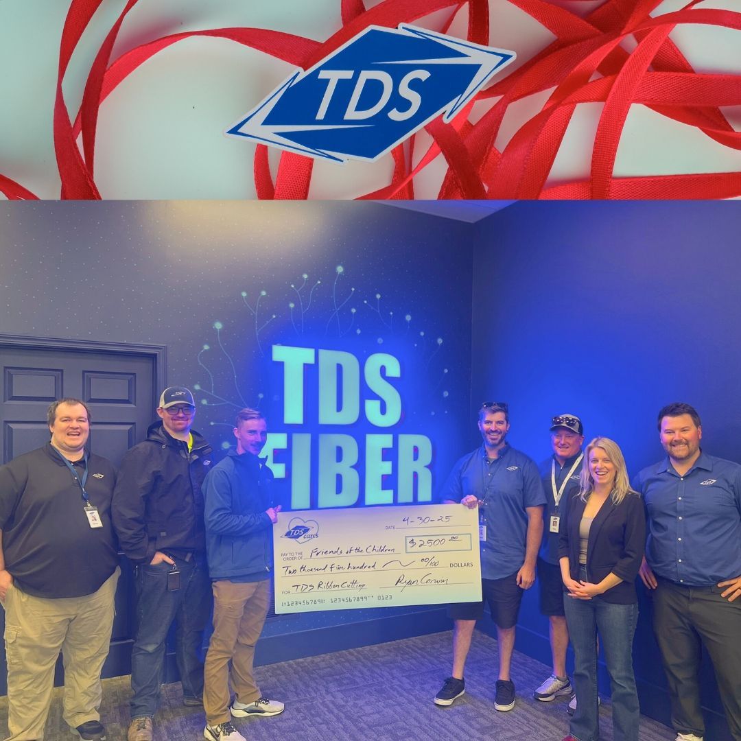 A group of people standing in front of a sign that says tds fiber