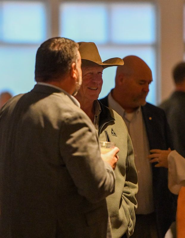 A man in a cowboy hat is talking to two other men