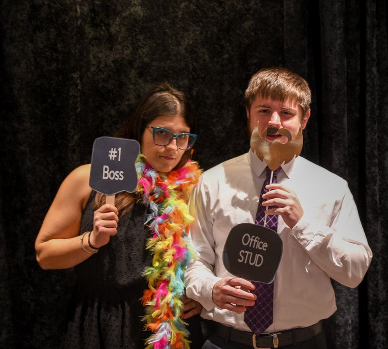 A man and a woman are posing for a picture and the woman is holding a sign that says # 1 boss