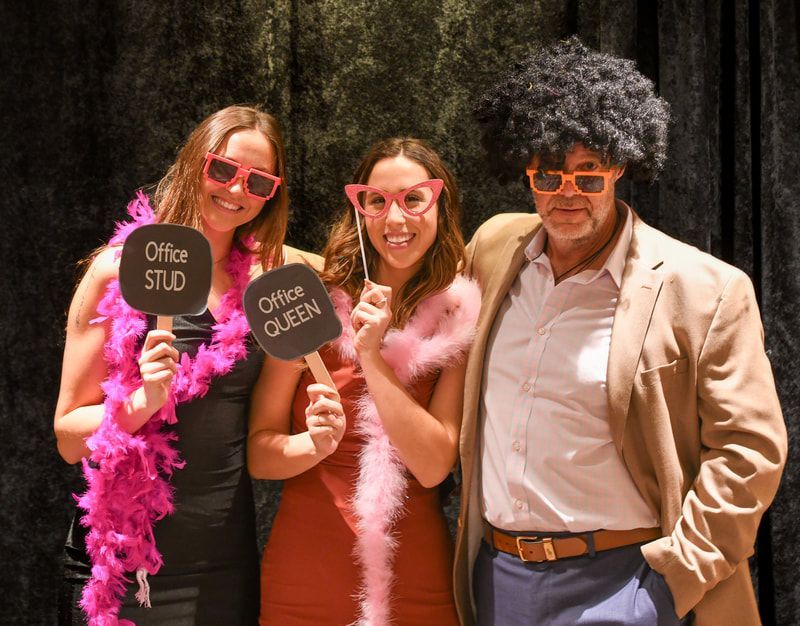 A man and two women holding signs that say office stud and office queen