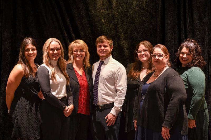 A group of people are posing for a picture in front of a black curtain.