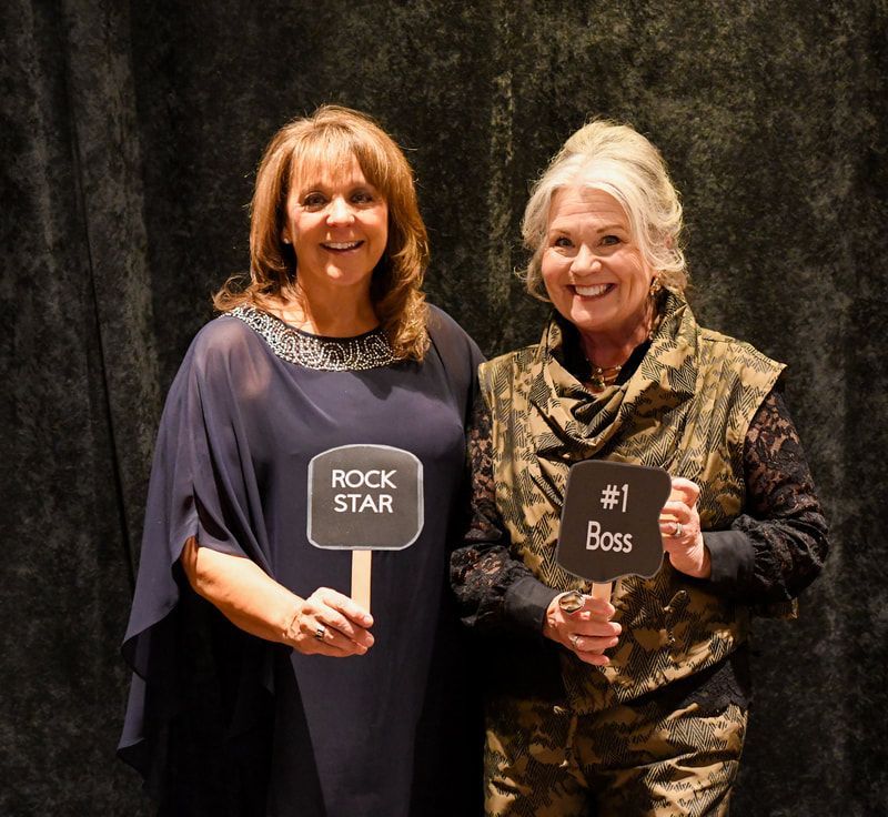 Two women holding signs that say rock star and # 1 boss