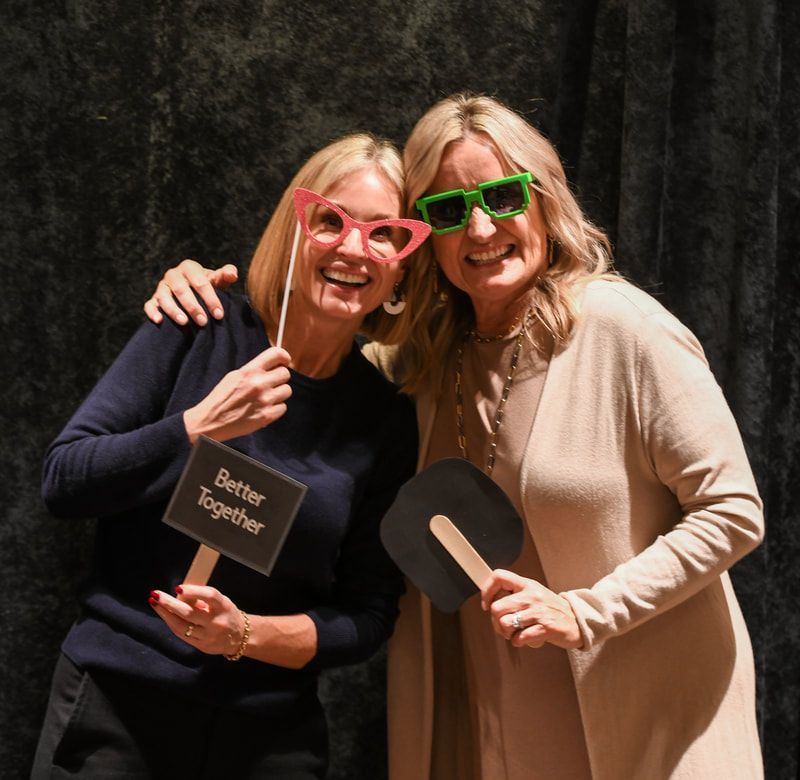 Two women holding a sign that says better together