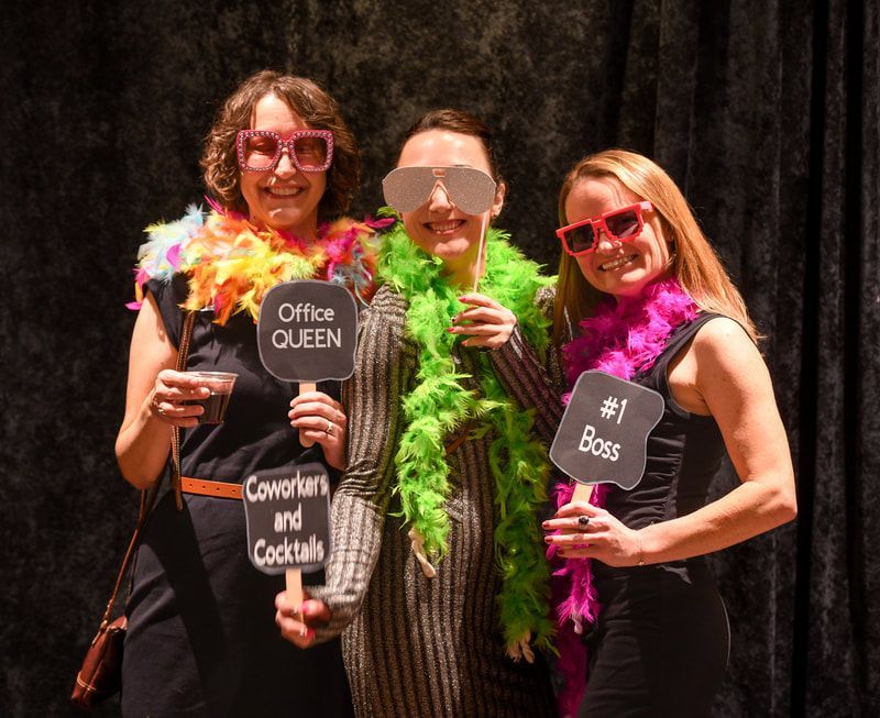 Three women are posing for a picture with signs in their hands.