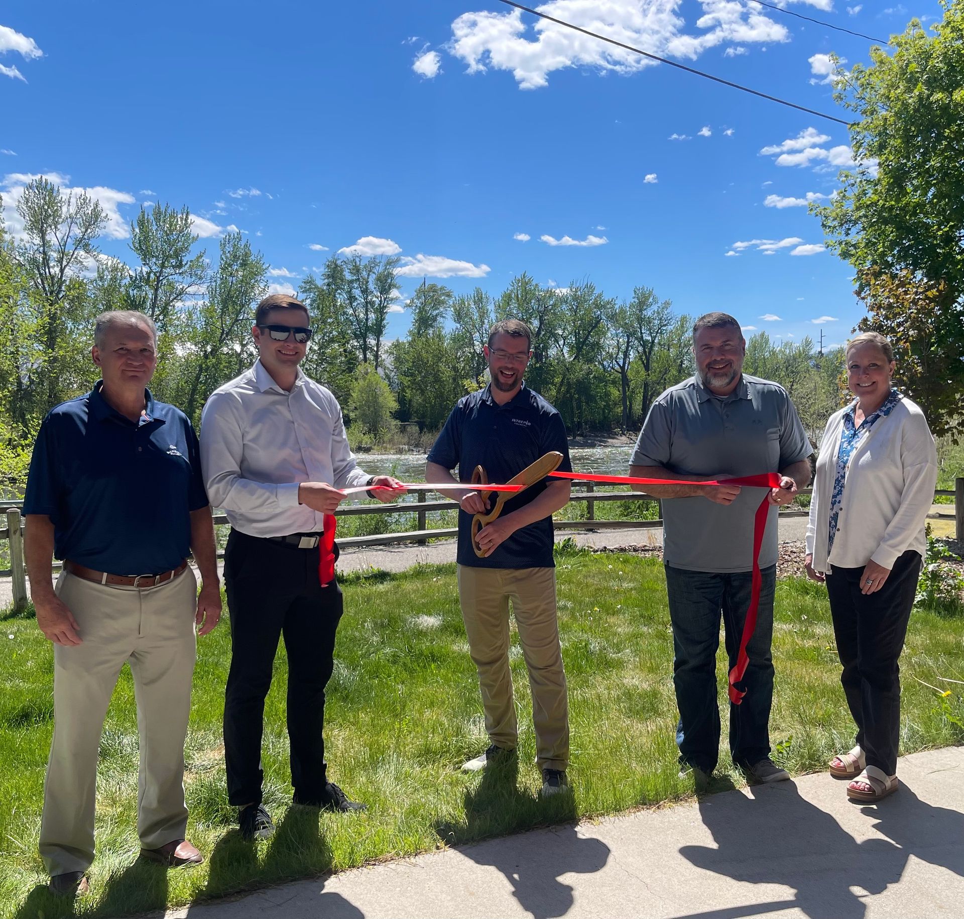 A group of people standing next to each other holding a red ribbon