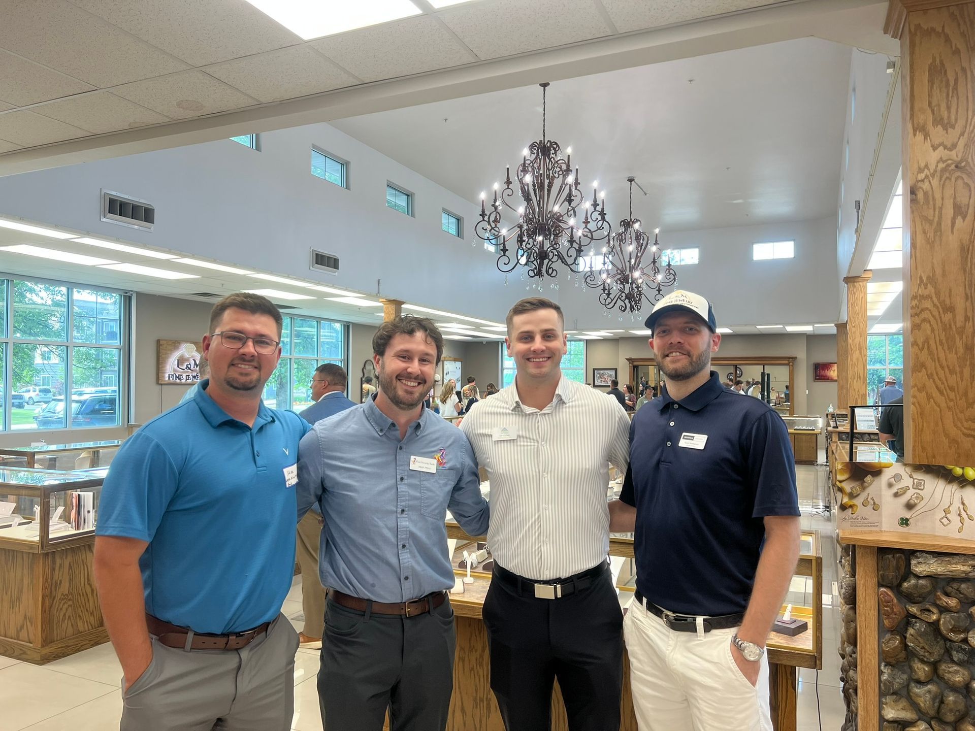 Four men are posing for a picture in a room with a chandelier.