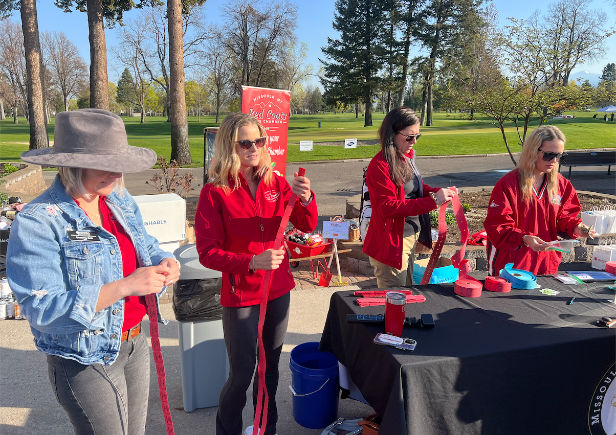 A group of women are standing around a table in a park.