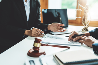 A group of people are sitting at a table with a gavel and a laptop.