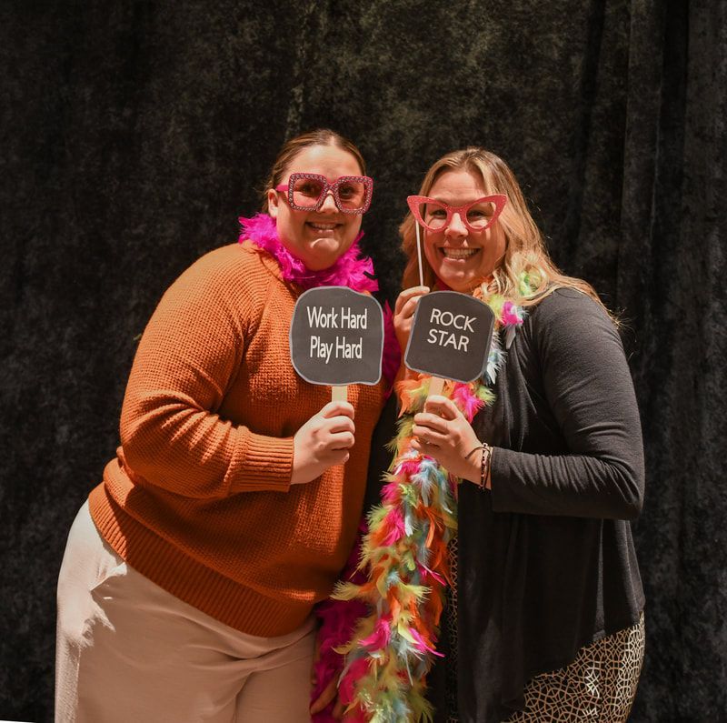Two women holding up signs that say work hard play hard and rock star