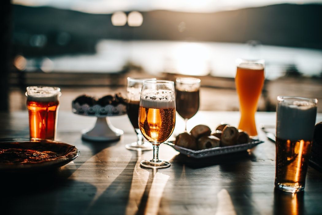 A table topped with glasses of beer and a plate of food.