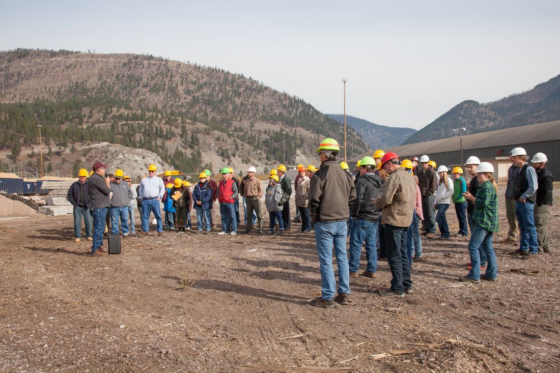 A group of people wearing hard hats are standing in a field.