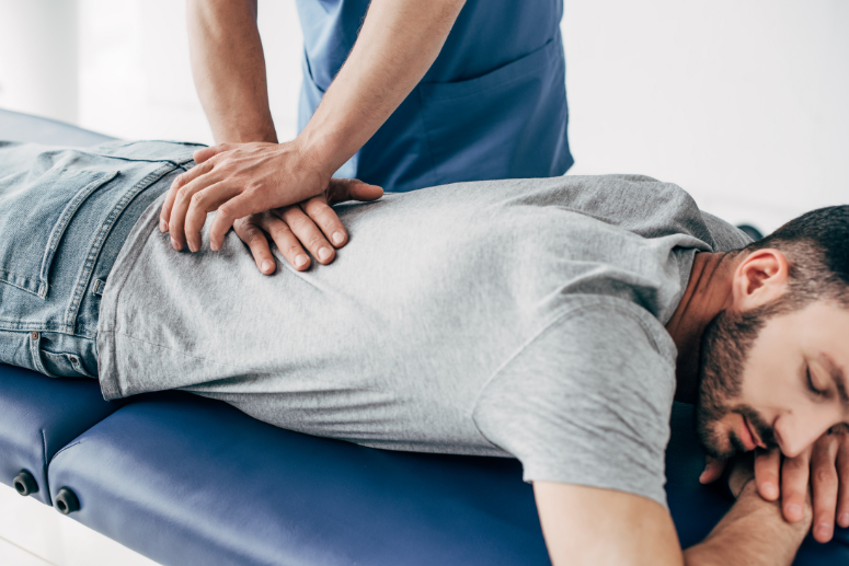 A man is laying on a table getting a massage from a doctor.